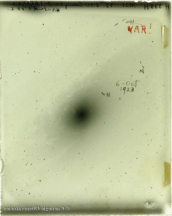 Black and white photograph on glass cover by exposed silver emulsion with a black spiral in the center and small black spots some of which are marked with an "n" for Nova and one of them sceatced out and written in red ink the word, "VAR!" for variable star.